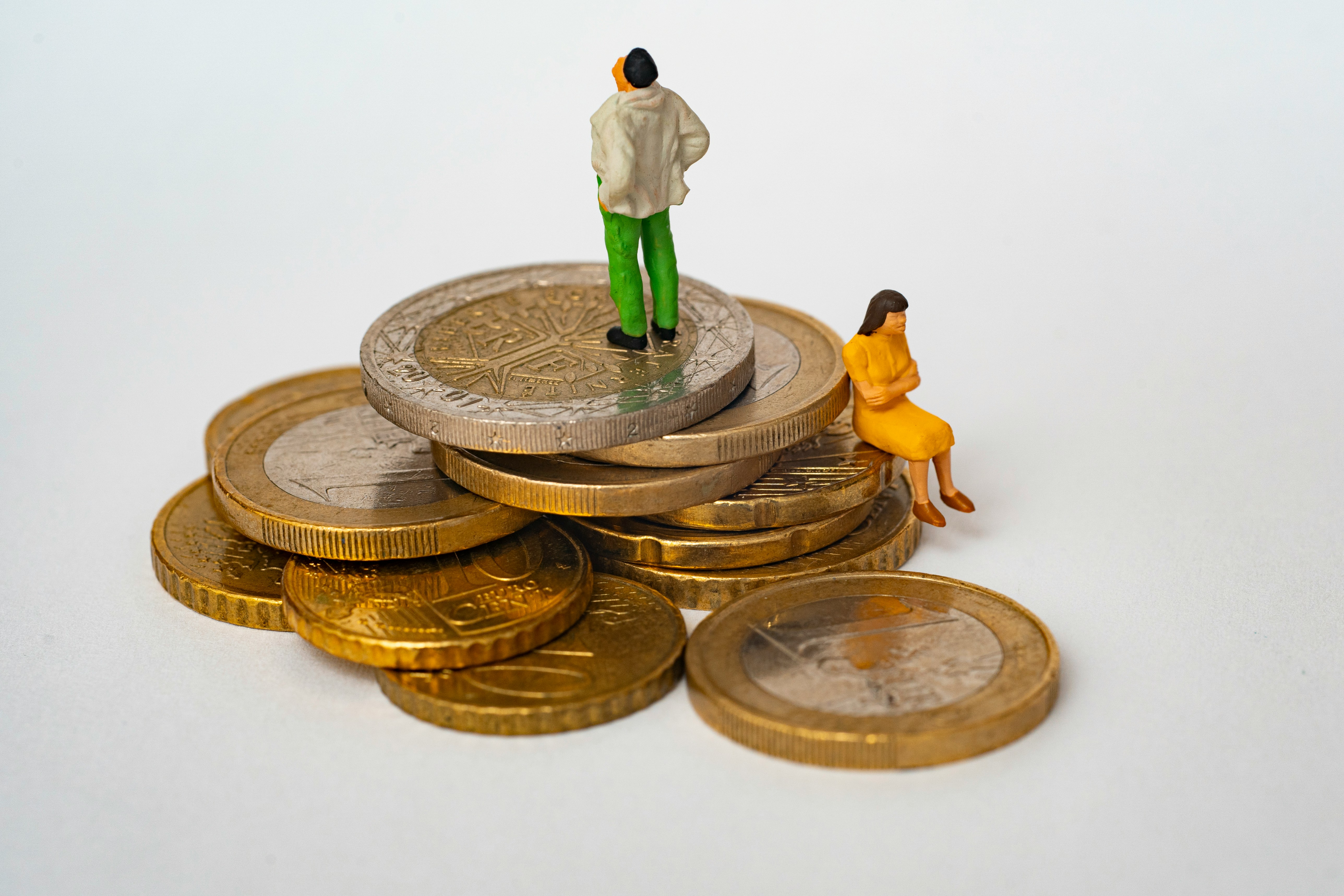 Two figures on a pile of coins, representing financial mediation between separating couples