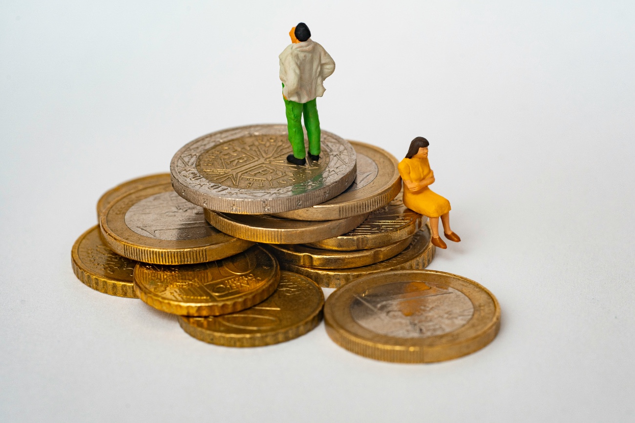 Two figures on a pile of coins, representing financial mediation between separating couples