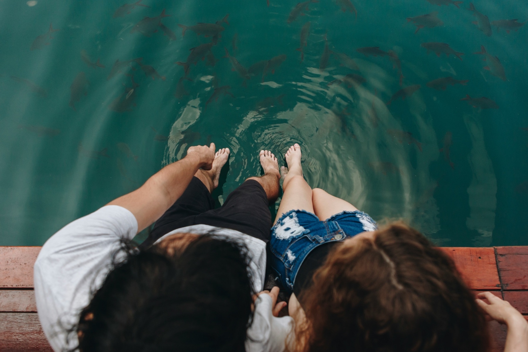 A family sitting on a jetty with their feet in the water